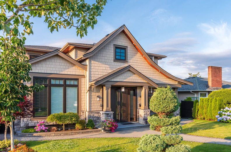 Front view of a craftsman-style house with stone accents and a manicured garden representing home resale value.